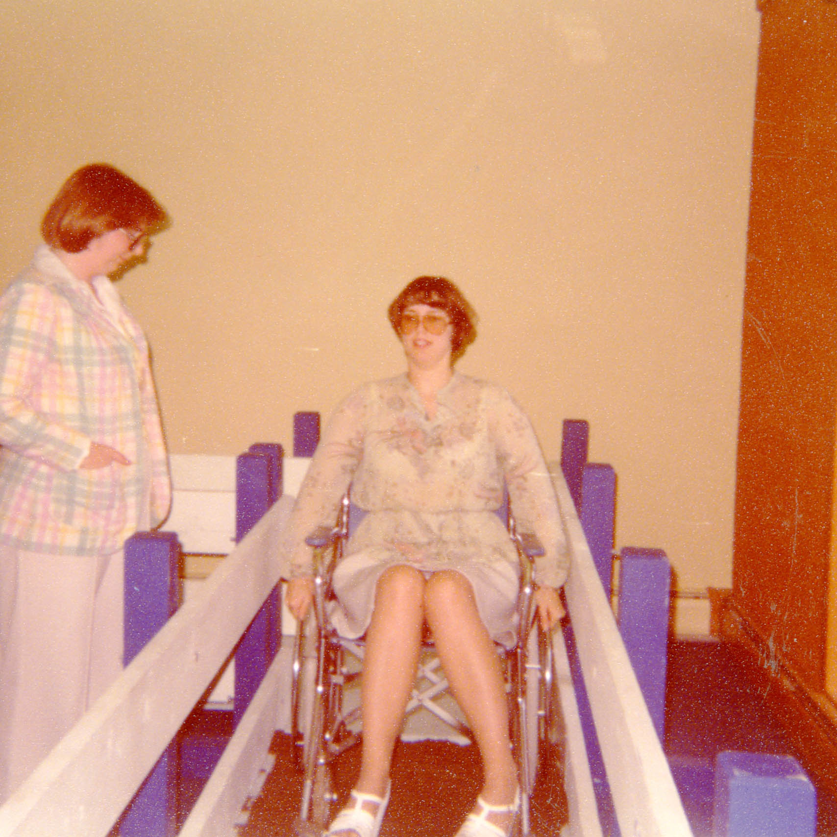 Person standing next to a person in a wheelchair using the wheelchair training course