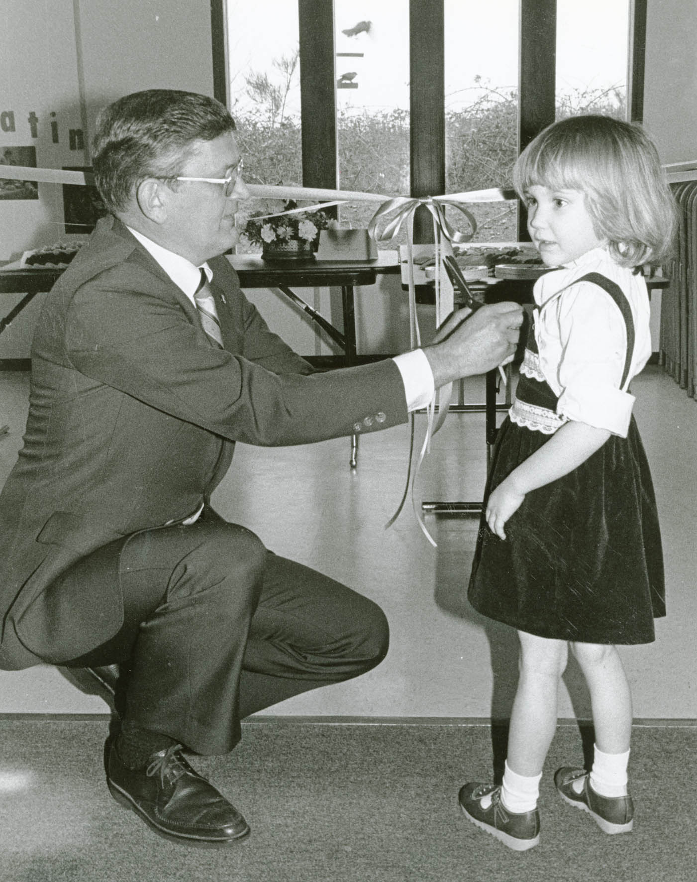 Man and small child next to the ribbon at the dedication of the child care center.